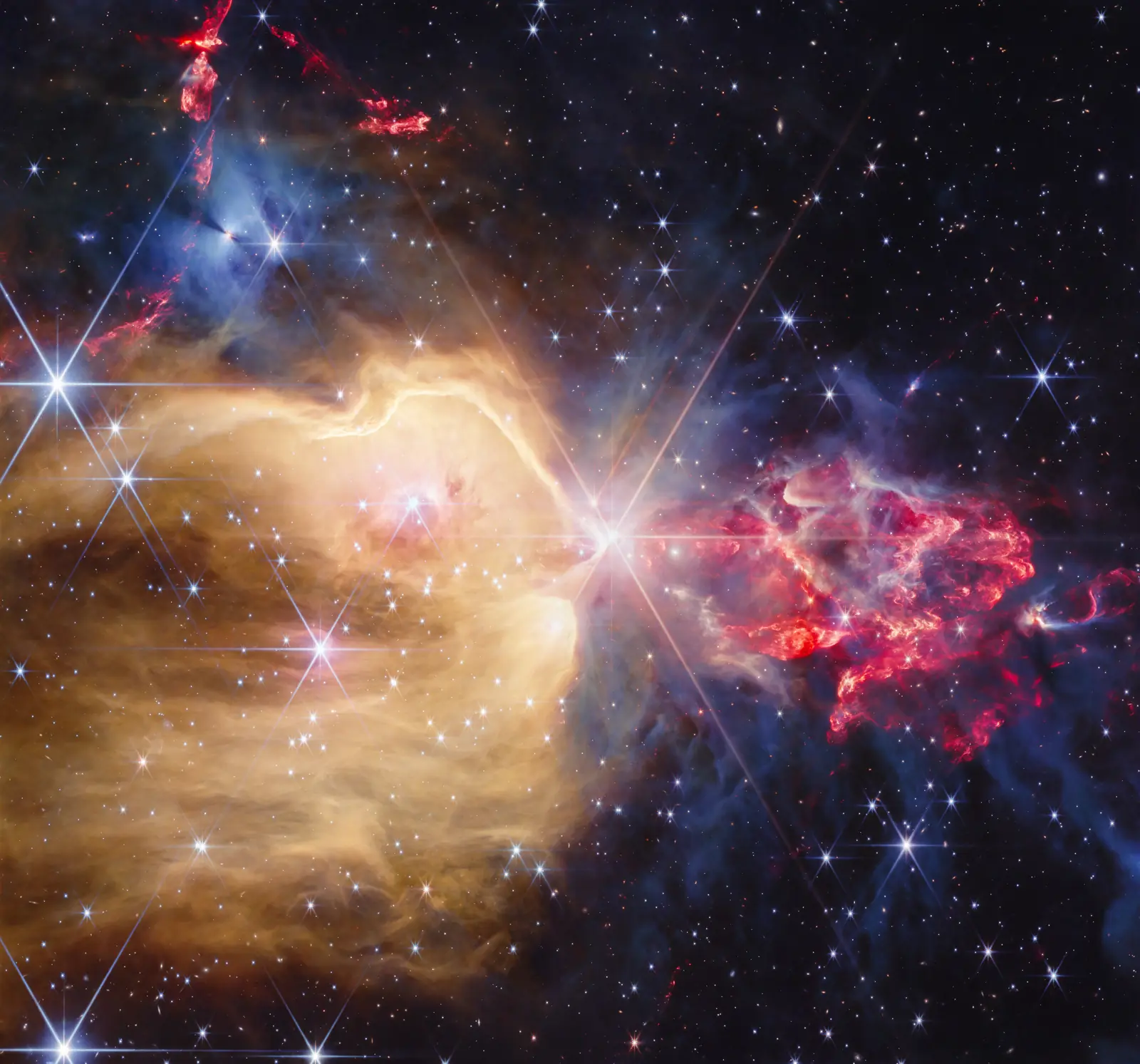 NGC 7129 observation with a bright central diffraction star, golden gas cavity on the left, red clumpy outflows on the right and dense gray-blue gas above.